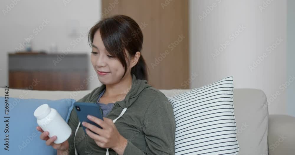 Woman check the ingredients of the bottle of medicine with cellphone at home