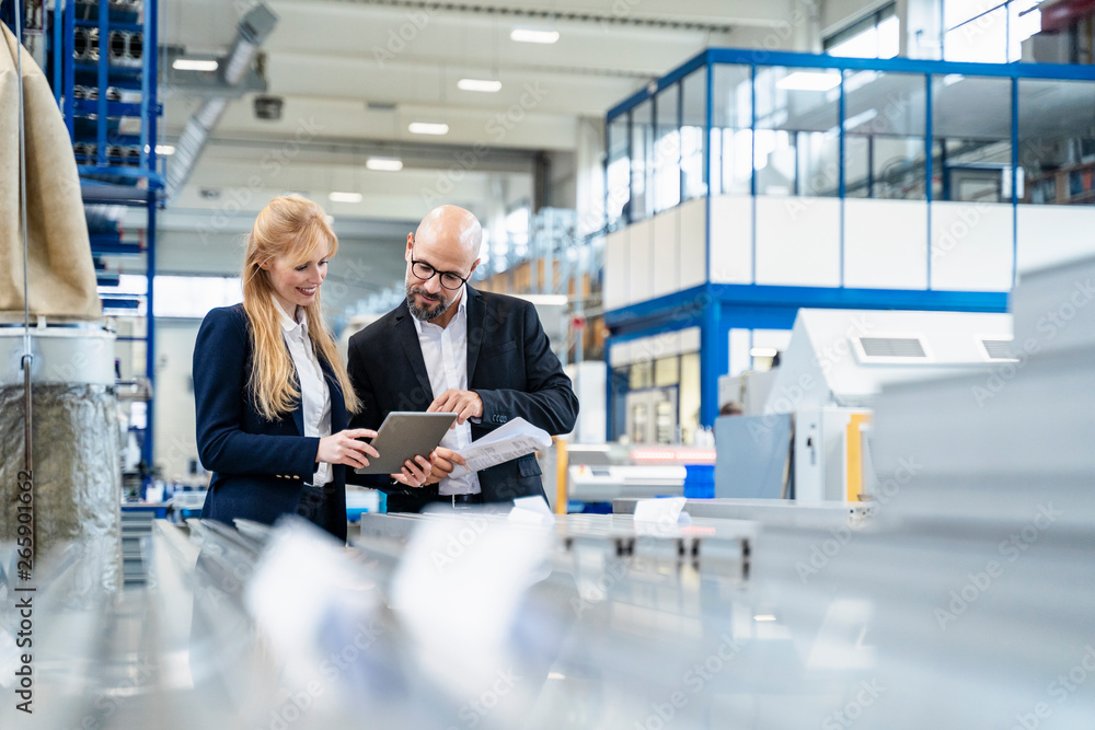 Businessman and businesswoman with tablet discussing in factory Businessman and businesswoman with tablet discussing in factory