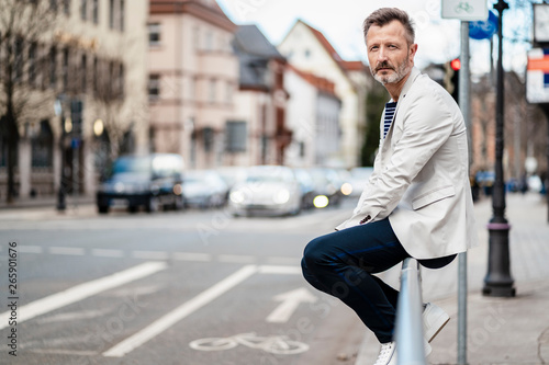 Germany, Zwickau, portrait of mature man sitting on railing in the city photo