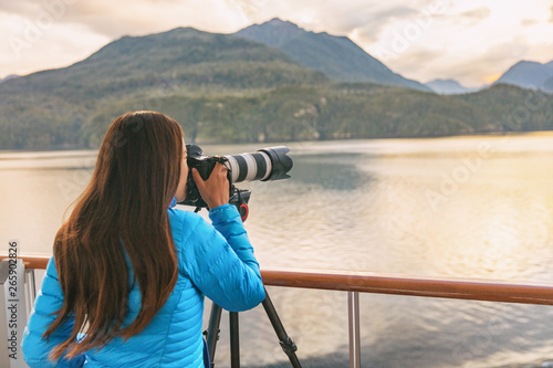 Travel photographer with professional telephoto lens camera on tripod shooting wildlife in Alaska, USA. Scenic cruising inside passage cruise tourist vacation adventure. Woman taking photo picture. photo