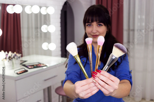 Girl holds makeup brushes in front of her