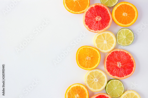 Colorful fruit side border of fresh citrus slices. Top view  flay lay over a white background with copy space.