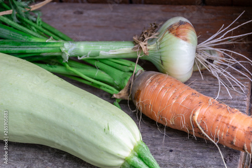 Healthy raw summer vegan vegetables and herbs, carrots, zucchini, onion on wood background. Healthy food, clean eating, top view, flat lay, copy space