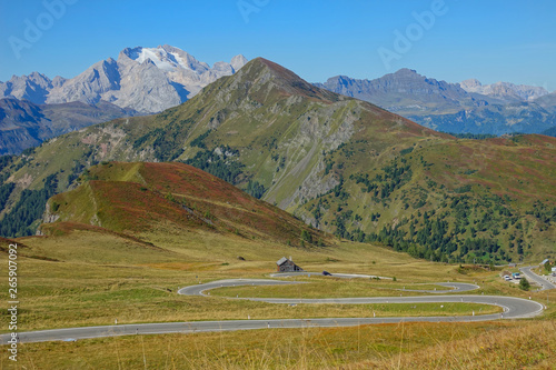 AERIAL: Flying over the pastures and towards a winding road in the mountains. © helivideo