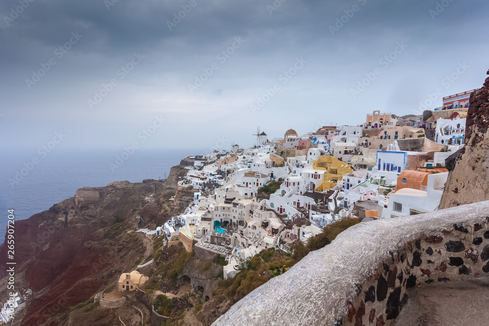 View of colorful houses of Oia and red cliffs on a rare rainy day