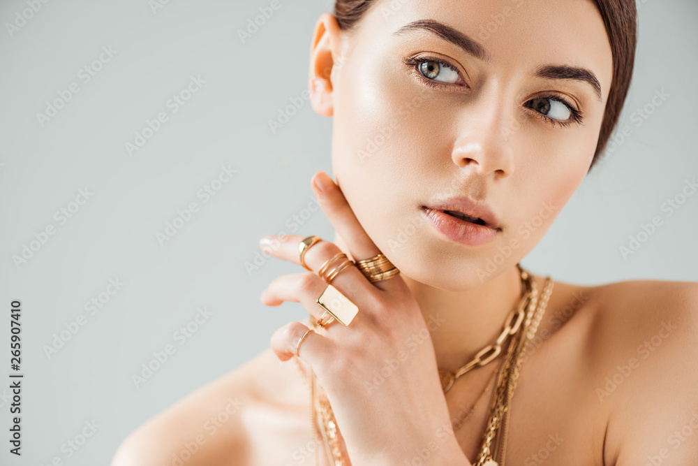 young nude woman in golden rings and necklaces looking away isolated on grey - obrazy, fototapety, plakaty 