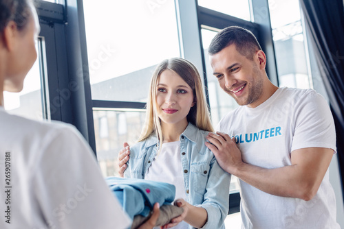 selective focus of attractive blonde woman taking clothes from multicultural volunteers