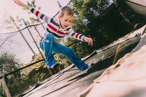 Child exercising in the backyard of his house jumping, casual portrait of his childhood.