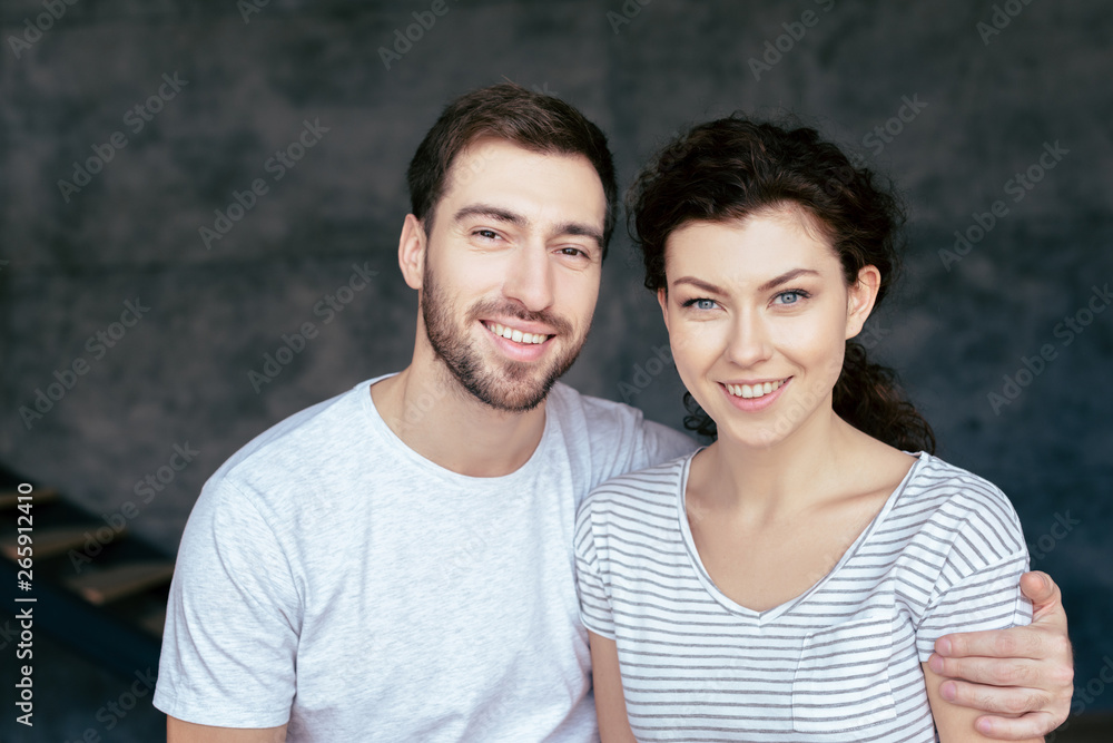 Obraz premium smiling bearded man embracing girlfriend and looking at camera