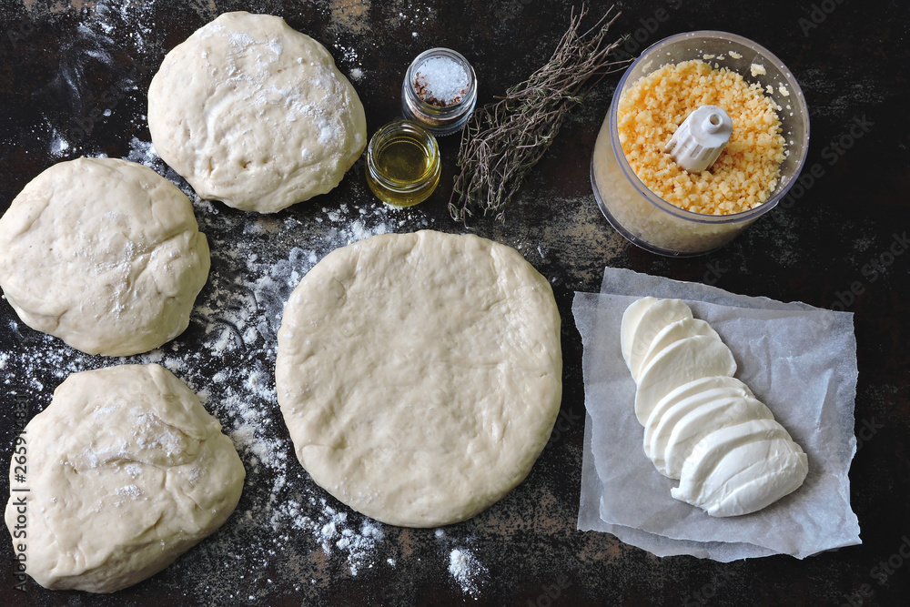 Cooking homemade pizza. Pizza dough, flour, mozzarella and grated cheese. Flat Lay. Cooking homemade pizza. Pizza dough, flour, mozzarella and grated cheese. Flat Lay.