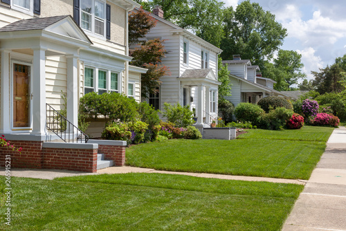 Beautifully manicured residential neighborhood lawns with well-maintained homes. © Noel