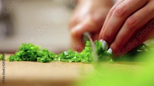 Close up rotation view of female hands professionally slicing cutting the green onion on the cutting board. Vegetables and fresh greens, vegetarian food, delicious flavor. Healthy lifestyle photo