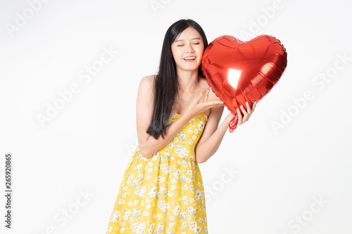 Asian young woman in yellow dress hold  red balloon heart. Young woman holding it with  being excited and surprised  holiday present isolated white  background.concept love surprise valentine day. © anon