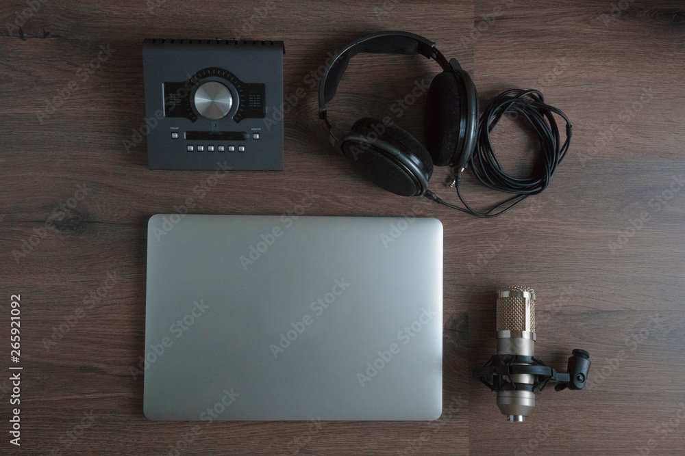 Flat lay of sound designers tools on dark wood table: laptop, sound card, headphones, microphone. Sound engineering tools. Professional sound card for music mixing and mastering Flat lay of sound designers tools on dark wood table: laptop, sound card, headphones, microphone. Sound engineering tools. Professional sound card for music mixing and mastering