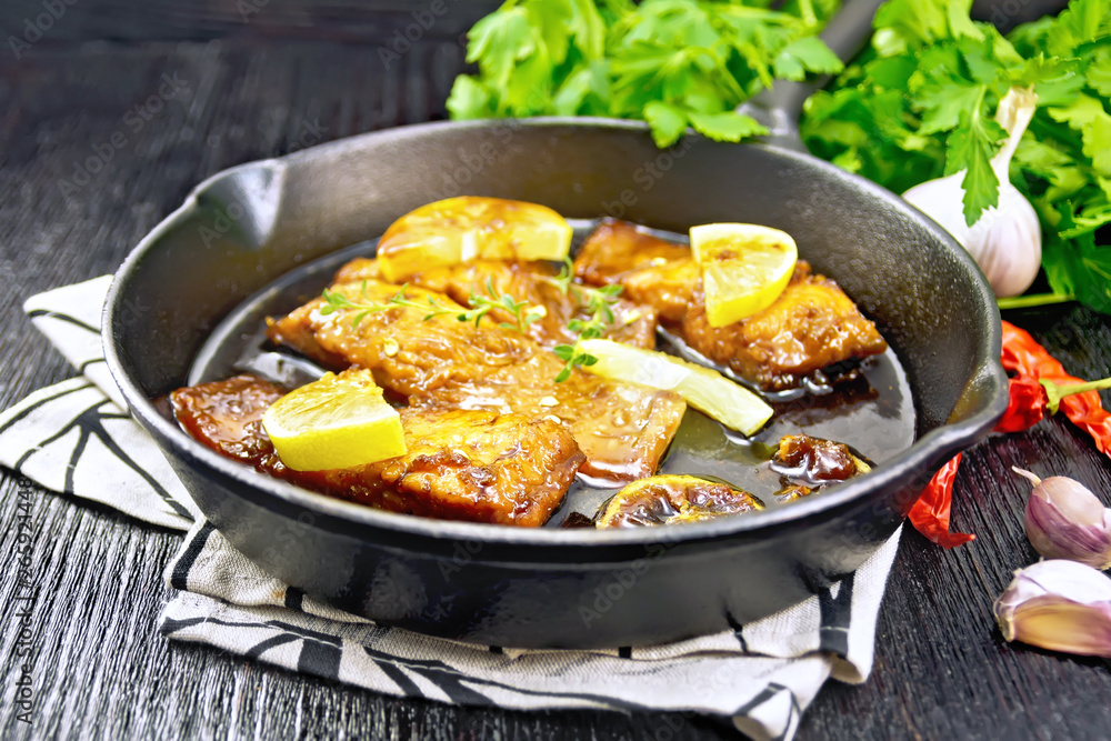 Salmon with sauce in pan on black wooden board Salmon with sauce in pan on black wooden board