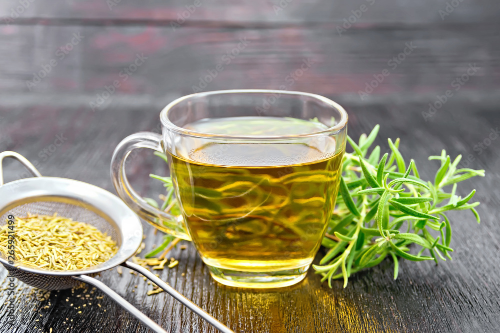 Tea of rosemary in cup with strainer on dark board Tea of rosemary in cup with strainer on dark board