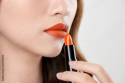Attractive woman applying orange lipstick © makistock