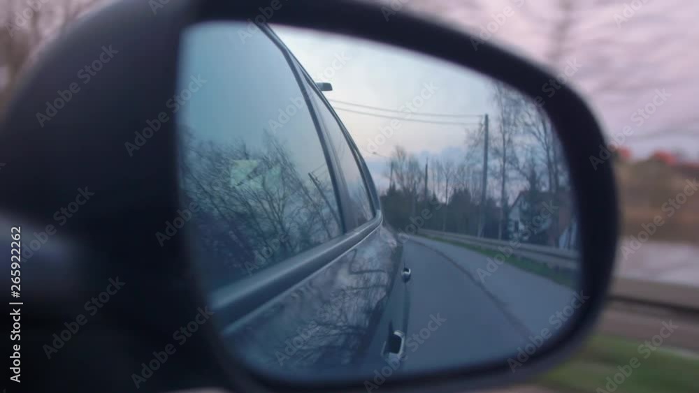 Side Mirror View of Car Driving by Trees and Houses Side Mirror View of Car Driving by Trees and Houses