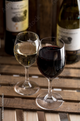 木の背景で赤ワインと白ワインのボトルとワイングラスがオシャレにおいてあるワインバー