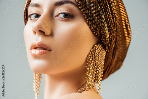 Obraz na plátně young beautiful woman with shiny make up, turban and golden earrings looking at