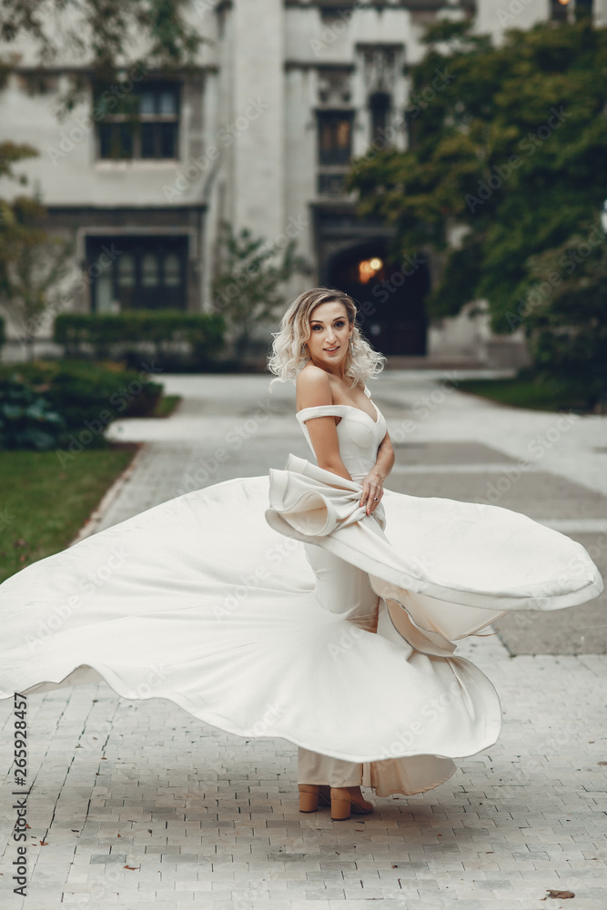 Beautiful bride in a long white dress. Woman with bouquet of flowers. Lady dancing in a park Beautiful bride in a long white dress. Woman with bouquet of flowers. Lady dancing in a park