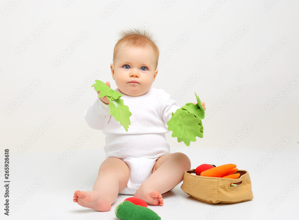Charming blue-eyed baby sitting on a white background with colored educational toys Charming blue-eyed baby sitting on a white background with colored educational toys