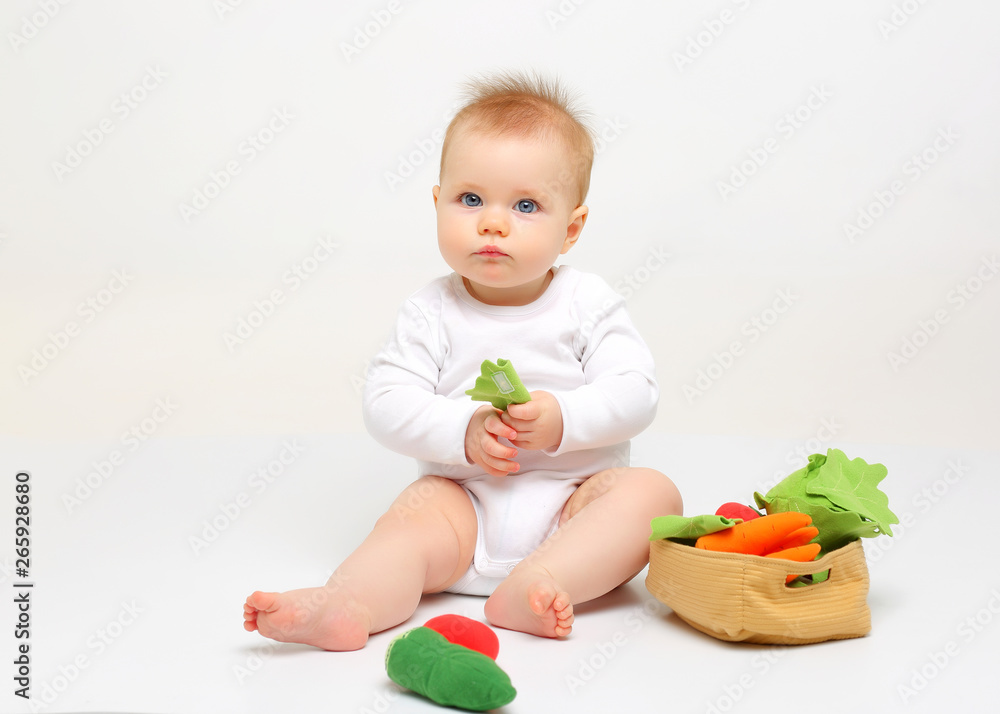 Charming blue-eyed baby sitting on a white background with colored educational toys Charming blue-eyed baby sitting on a white background with colored educational toys