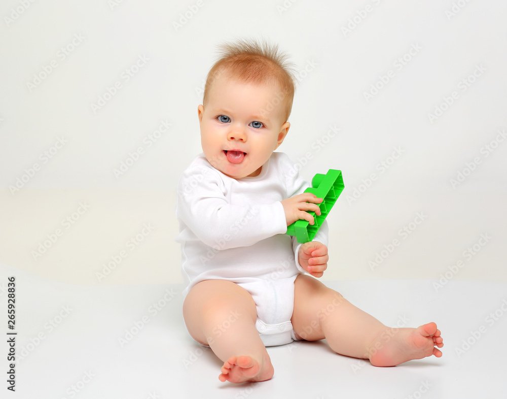 Charming blue-eyed baby sitting on a white background with colored educational toys Charming blue-eyed baby sitting on a white background with colored educational toys