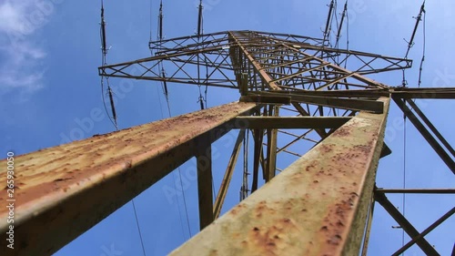 Old Rusty Transmission Tower and High Voltage Power Lines on Blue Sky Background