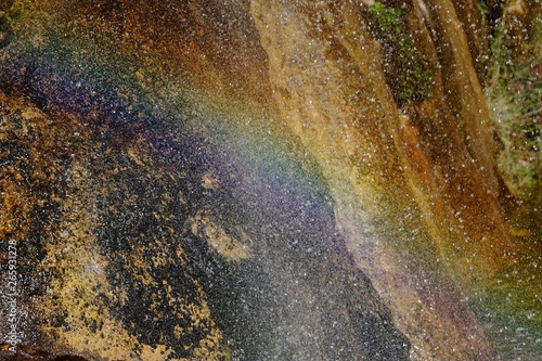A rainbow is created where water from a waterfall hit the bottom 