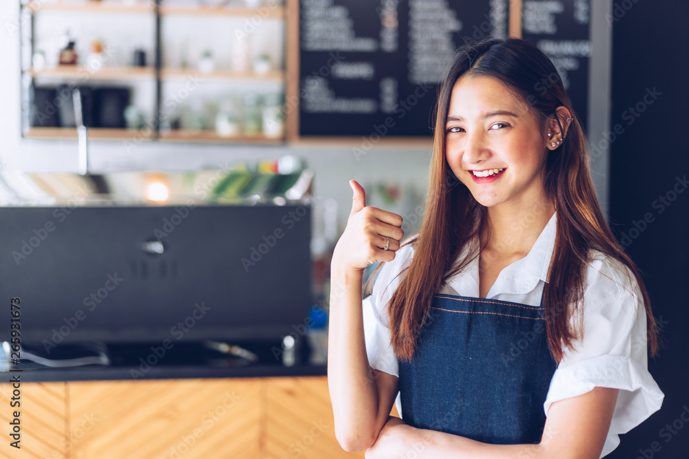Pretty young asian waitress standing arms crossed in cafeteria.Coffee Business owner Concept. barista in apron smiling at camera in coffee shop counter Pretty young asian waitress standing arms crossed in cafeteria.Coffee Business owner Concept. barista in apron smiling at camera in coffee shop counter