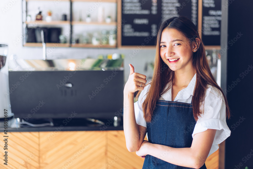 Pretty young asian waitress standing arms crossed in cafeteria.Coffee Business owner Concept. barista in apron smiling at camera in coffee shop counter Pretty young asian waitress standing arms crossed in cafeteria.Coffee Business owner Concept. barista in apron smiling at camera in coffee shop counter