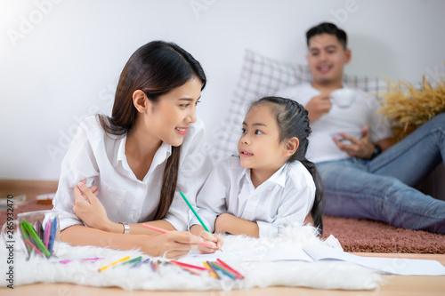 Young family drawing together with colorful pencils at home