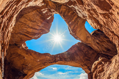 Amazing rock formations at Arches National Park in southern Utah. View from below of Double Arch looking back up at the sun. photo
