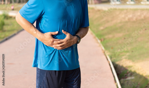 side stitch during running, close up young man holding abdominal