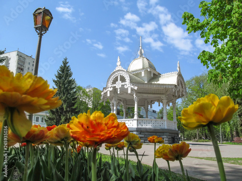 Sumy, Ukraine - April 28, 2019: Park on Pokrovsky Square with a flower bed and vintage wooden carved arbor in Sumy. Beautiful spring view of the main historical and tourist attraction of the city