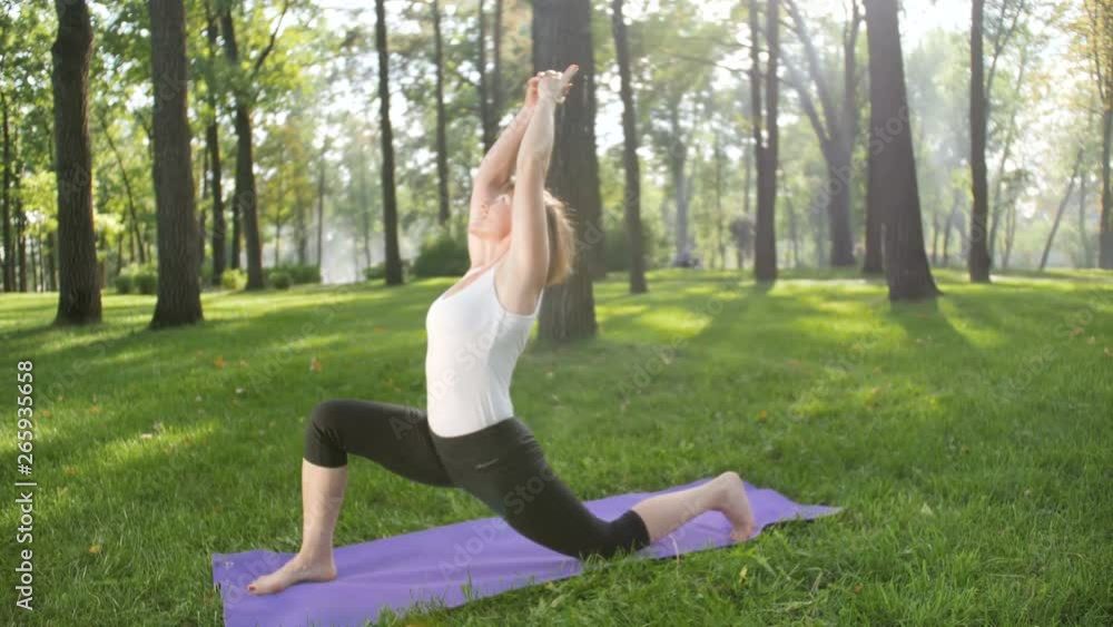 4k slow motion video of beautiful smiling middle aged woman doing yoga exercises and stretching in park. It is very useful for mental and physical health. People relaxing at nature 4k slow motion video of beautiful smiling middle aged woman doing yoga exercises and stretching in park. It is very useful for mental and physical health. People relaxing at nature