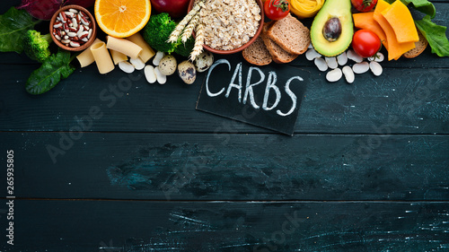 Foods high in carbohydrates: bread, pasta, avocado, flour, pumpkin, broccoli, beans, spinach. The concept of healthy eating. On a black background.