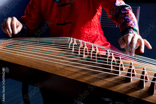 A woman's hands playing the Chinese Guzheng or Zheng, a popular traditional stringed instrument in beautiful natural light photo