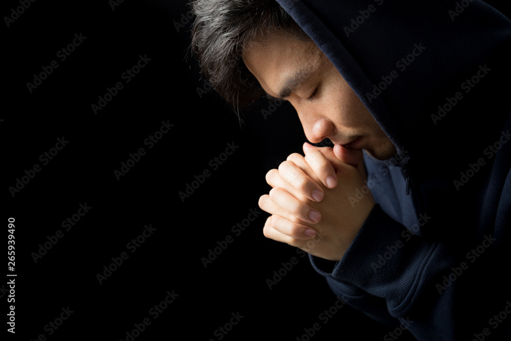 © christianchan - Praying Man Against Dark Background With Copy Space