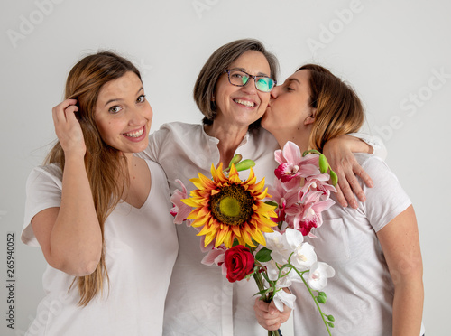 mother and two twin sisters enjoy in very funny attitude with a big sunflower in their hands
