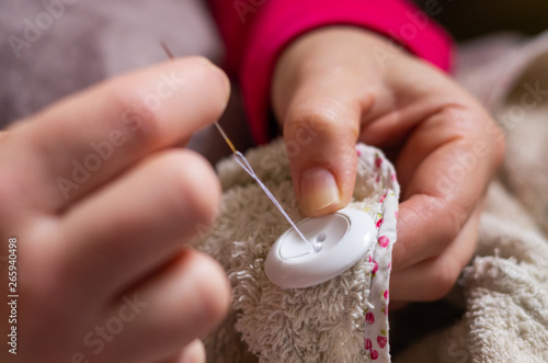 Woman sewing a button with thread and needle