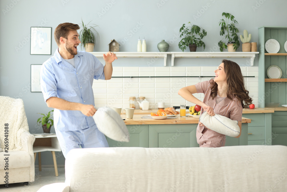 Happy loving couple having fun while having a pillow fight in the living room. Happy loving couple having fun while having a pillow fight in the living room.