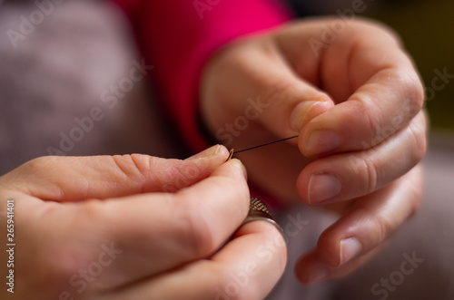 Woman cutting and knotting a thread on a needle