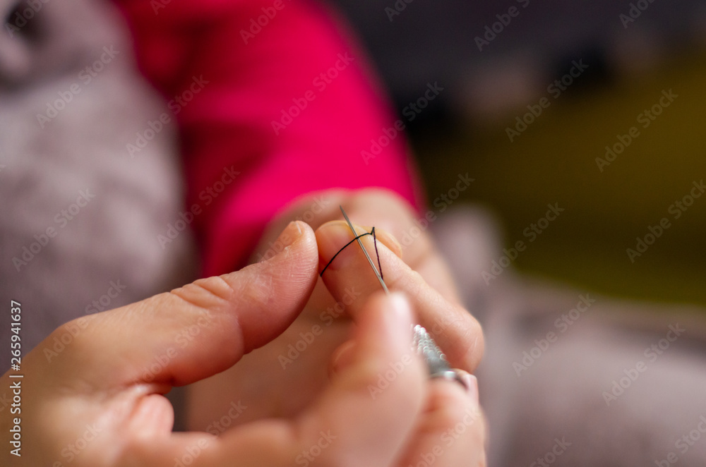 Woman cutting and knotting a thread on a needle Woman cutting and knotting a thread on a needle