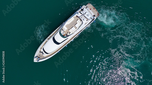 Aerial drone bird's eye top view photo of luxury yacht with wooden deck docked in deep blue waters of Mykonos island, Cyclades, Greece © aerial-drone