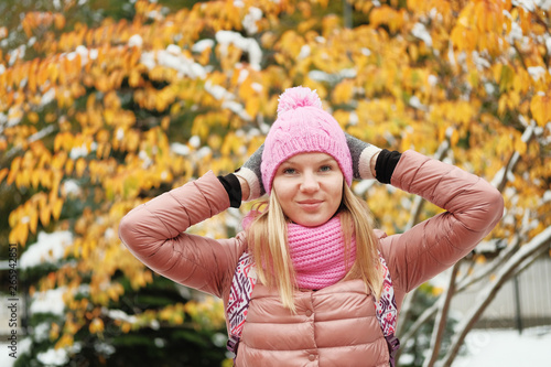 Portrait of beautiful blond girl posing for photo at winter mountain with yellow leaves