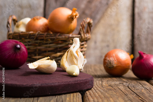 onions and garlics on cutting board, weathered wooden background