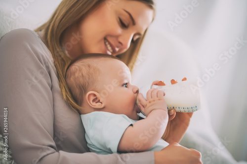 Happy mother is feeding her baby boy at home. photo