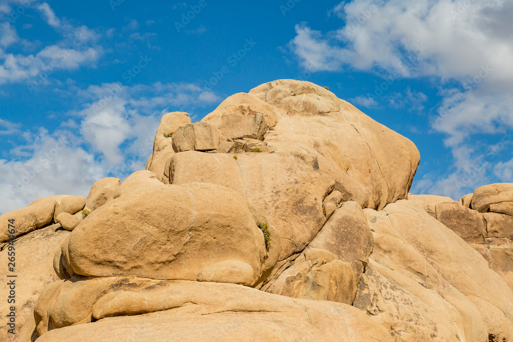 Large rock formations in Joshua Tree National Park, with a blue sky overhead Large rock formations in Joshua Tree National Park, with a blue sky overhead